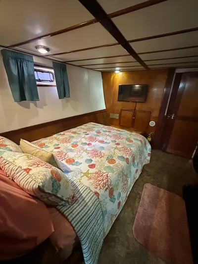 Boatel I Yacht Photos Pics Cozy bedroom in a 1998 custom 65-foot trawler with floral bedding and wood paneling.