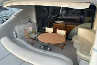 Luxurious seating area on a 2005 Pershing 76 yacht with round table and chairs.