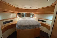 Luxurious bedroom interior of a 2005 Pershing 76 yacht with elegant wood finishes.
