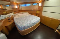 Luxurious bedroom interior of a 2005 Pershing 76 yacht with elegant wood finishes.