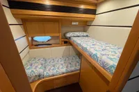 Cozy twin cabin with nautical-themed bedding in a 2005 Pershing 76 yacht.
