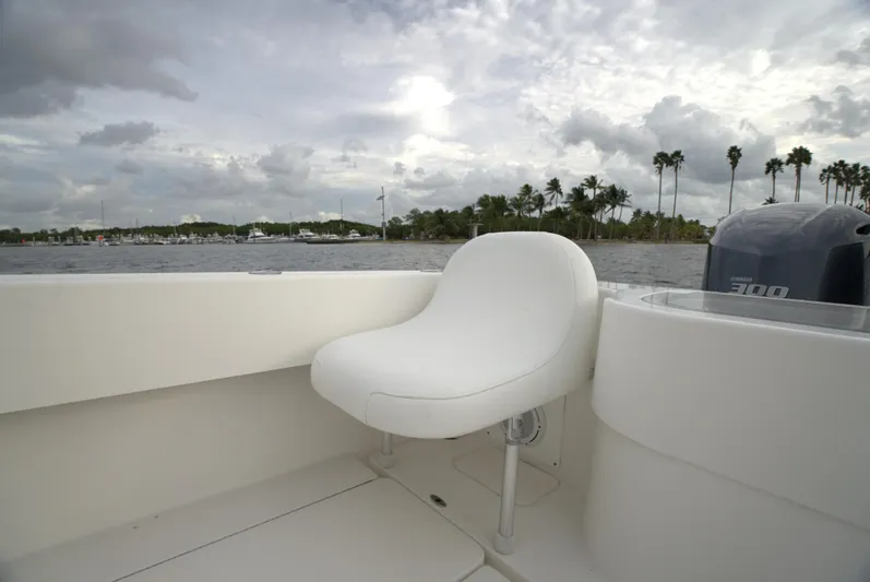  Yacht Photos Pics Invincible 33 boat interior with white seating, 2012 model, on a cloudy day near palm trees.
