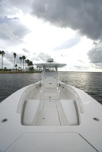  Yacht Photos Pics Invincible 33 boat on water, cloudy sky, palm trees in background, 2012 model.