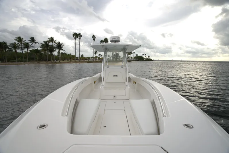  Yacht Photos Pics Invincible 33 boat, 2012 model, cruising near a tropical shoreline under cloudy skies.