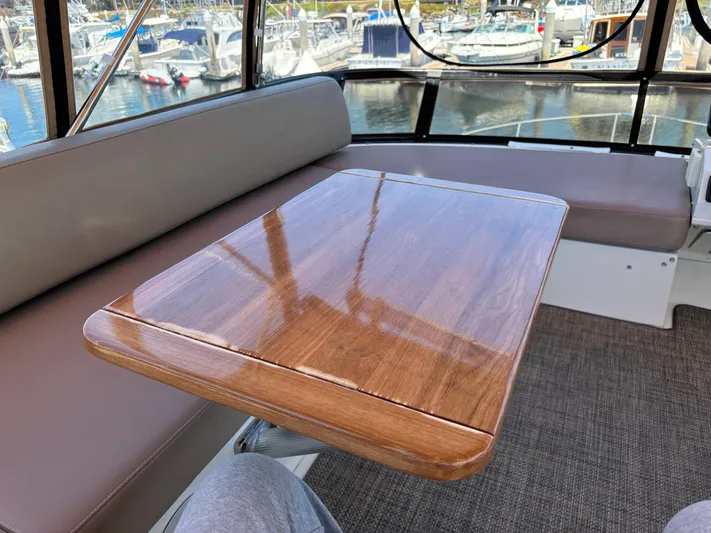  Yacht Photos Pics Interior of 2014 Carver C34 yacht with polished wooden table and cushioned seating.