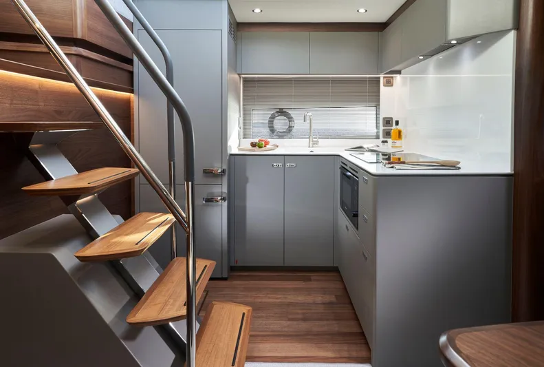 50 Princess V50 2026 Yacht Photos Pics Modern kitchen interior of 2026 Princess V50 Deck Salon yacht, featuring sleek cabinetry and wooden accents.
