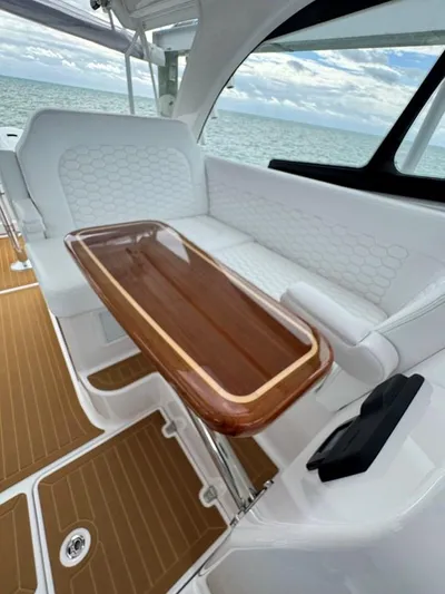  Yacht Photos Pics 2023 Southport 33 DC boat interior with elegant seating and wooden table, overlooking the ocean.