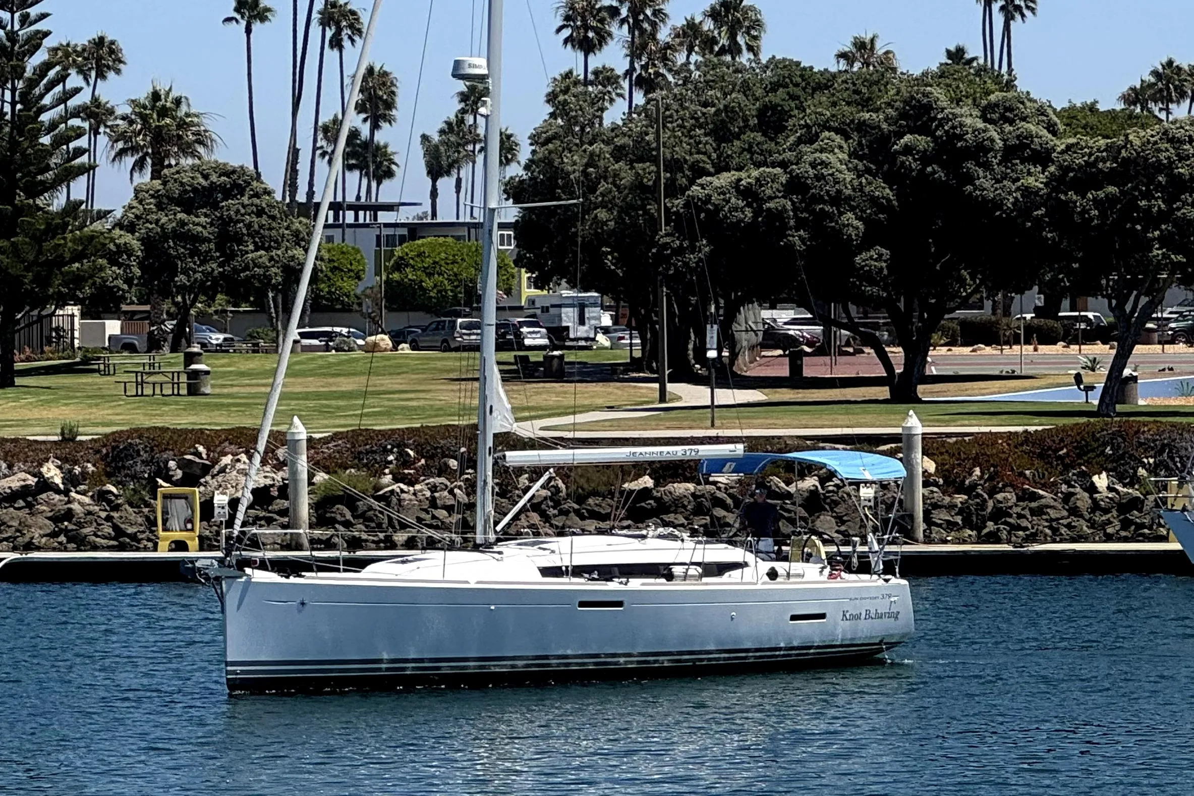 2014 Jeanneau Sun Odyssey 379 sailboat docked near a park with palm trees.
