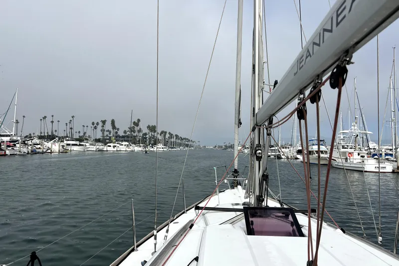 Knot Behaving Yacht Photos Pics 2014 Jeanneau Sun Odyssey 379 sailing in a marina with palm trees and boats.