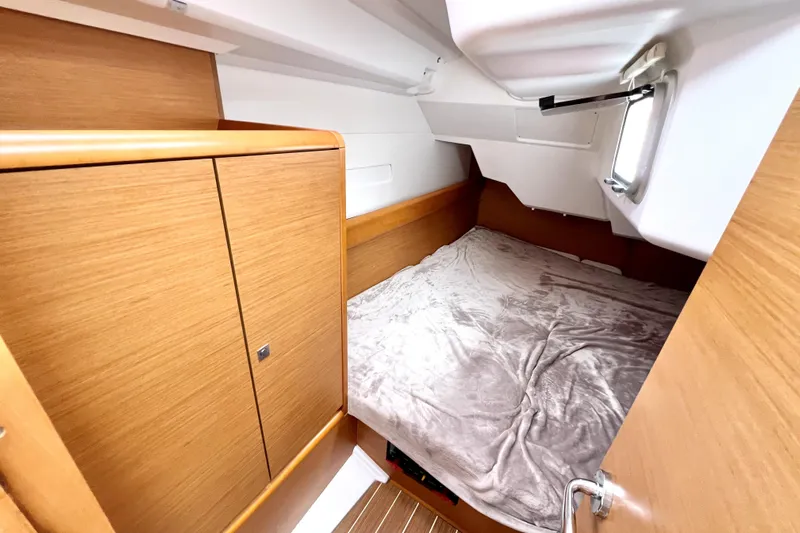Knot Behaving Yacht Photos Pics 2014 Jeanneau Sun Odyssey 379 cabin with cozy bed and wooden cabinetry.