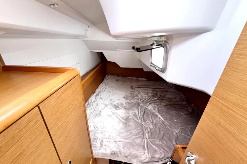 Knot Behaving Yacht Photos Pics 2014 Jeanneau Sun Odyssey 379 cabin interior with cozy bed and wooden cabinetry.