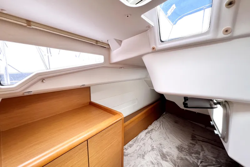 Knot Behaving Yacht Photos Pics Interior cabin of 2014 Jeanneau Sun Odyssey 379 sailboat, featuring wood cabinetry and windows.