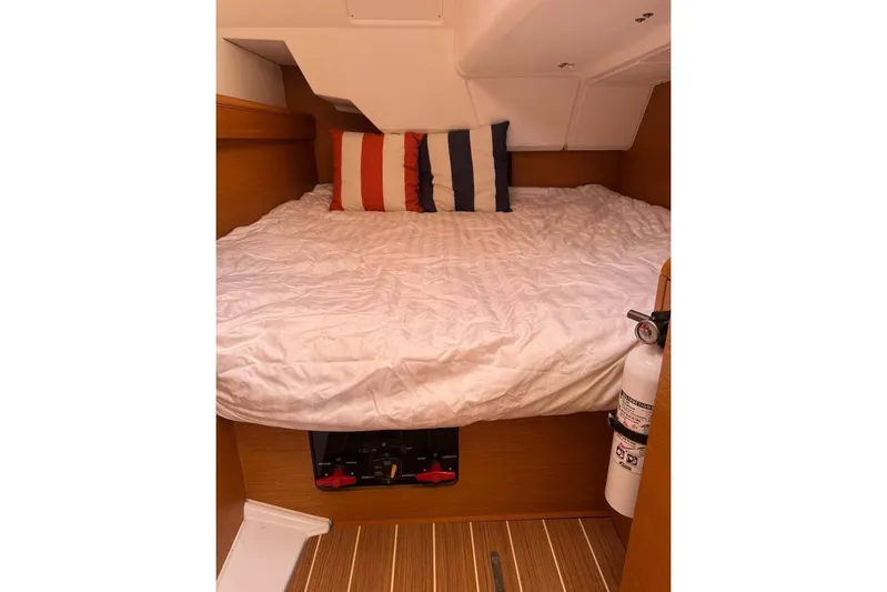 Knot Behaving Yacht Photos Pics Cozy cabin interior of 2014 Jeanneau Sun Odyssey 379 with striped pillows and fire extinguisher.