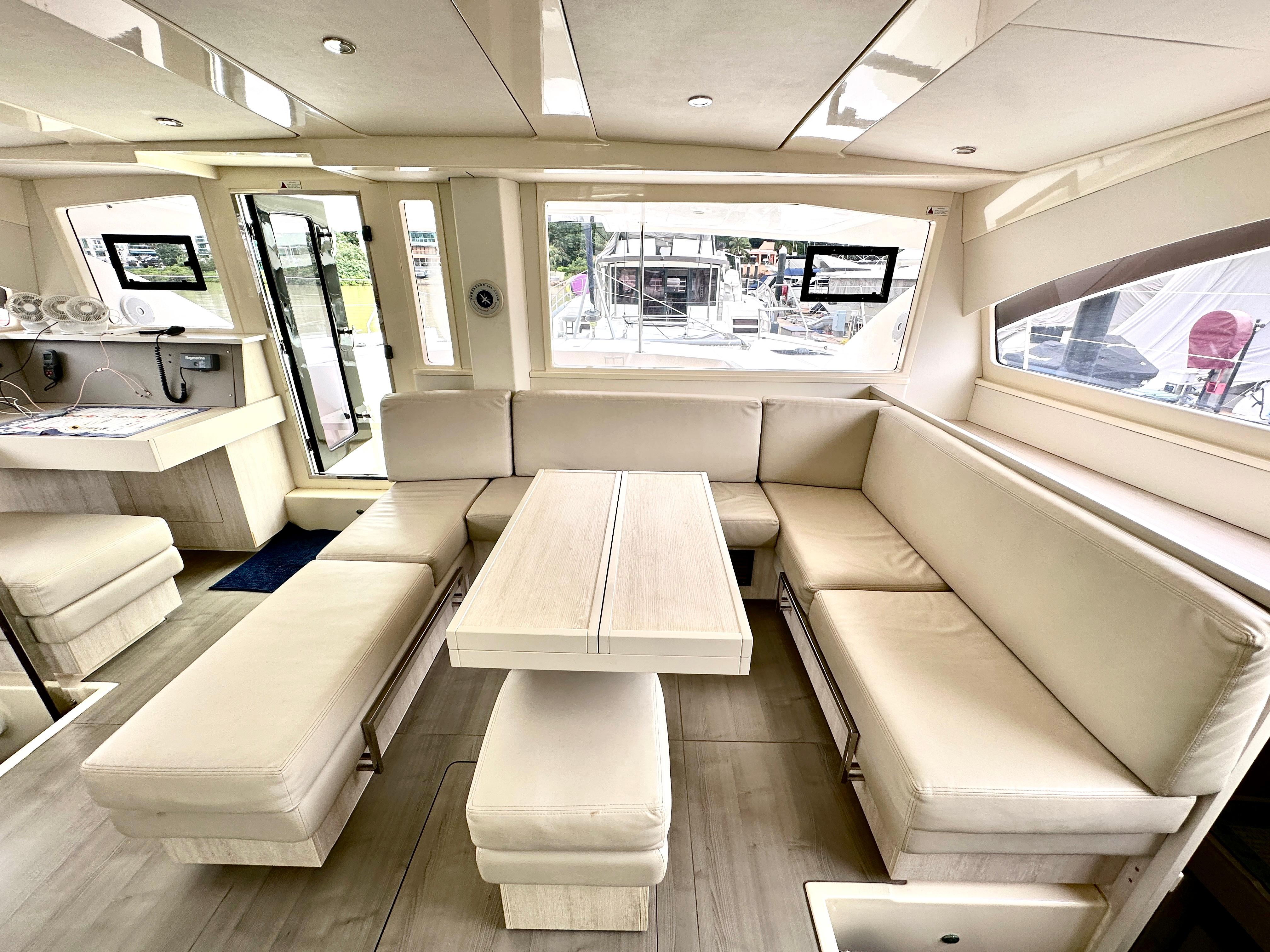 Luxurious interior of a 2015 Leopard 48 yacht with beige seating and large windows.