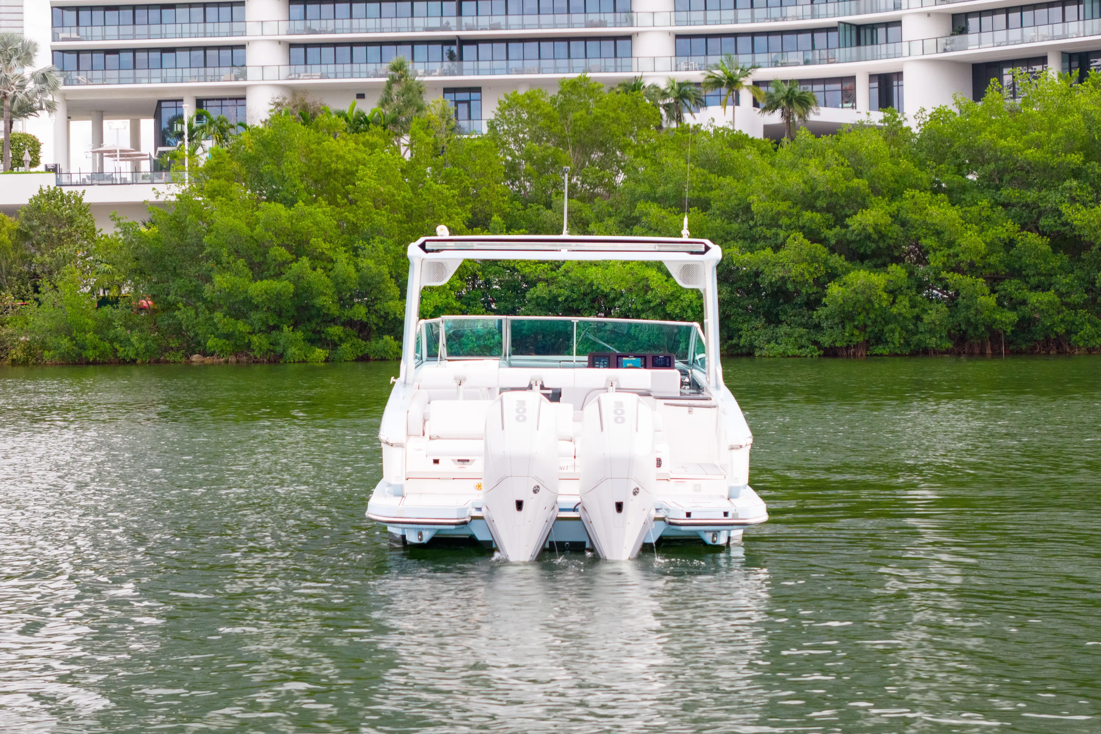  Yacht Photos Pics 2022 Aviara AV32 OB boat on water, with modern building and greenery in background.