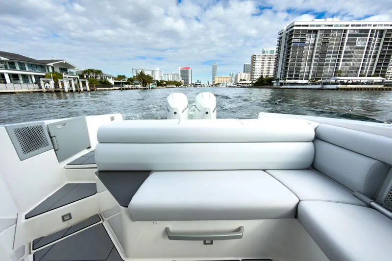  Yacht Photos Pics 2022 Aviara AV32 OB boat with luxurious seating, cruising near waterfront buildings.