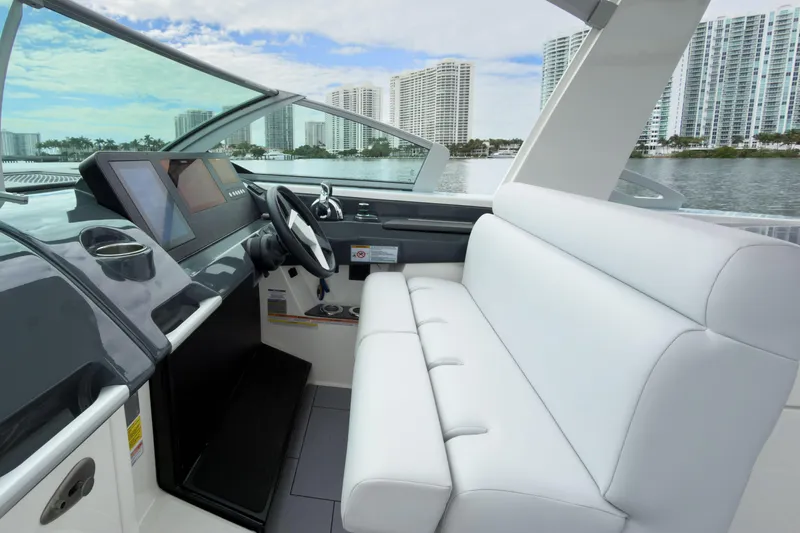  Yacht Photos Pics 2022 Aviara AV32 OB boat interior with modern helm and white seating, cityscape in background.