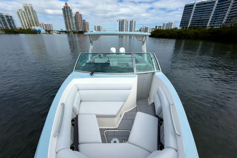  Yacht Photos Pics 2022 Aviara AV32 OB boat with sleek design on a calm waterway, city skyline backdrop.