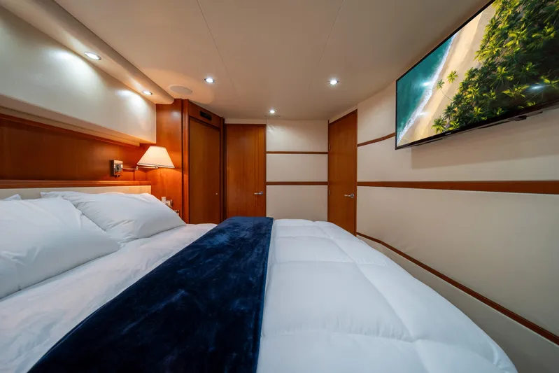 Jobsite Yacht Photos Pics Luxurious bedroom interior of 2009 Bertram 630 yacht with cozy bedding and wall-mounted TV.