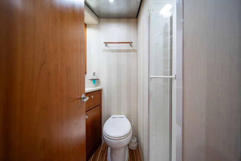 Jobsite Yacht Photos Pics Compact bathroom in a 2009 Bertram 630 yacht with wooden cabinetry and shower.