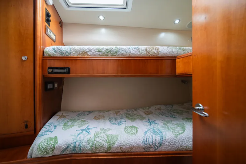 Jobsite Yacht Photos Pics Bunk beds in the 2009 Bertram 630 yacht cabin with wooden interior and patterned bedding.