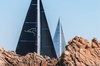 Sailing yachts with black sails near rocky coastline, Solaris 64 RS, 2022 model.