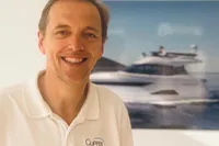Man smiling in front of a Solaris 64 RS yacht poster, wearing Clipper Marine polo.