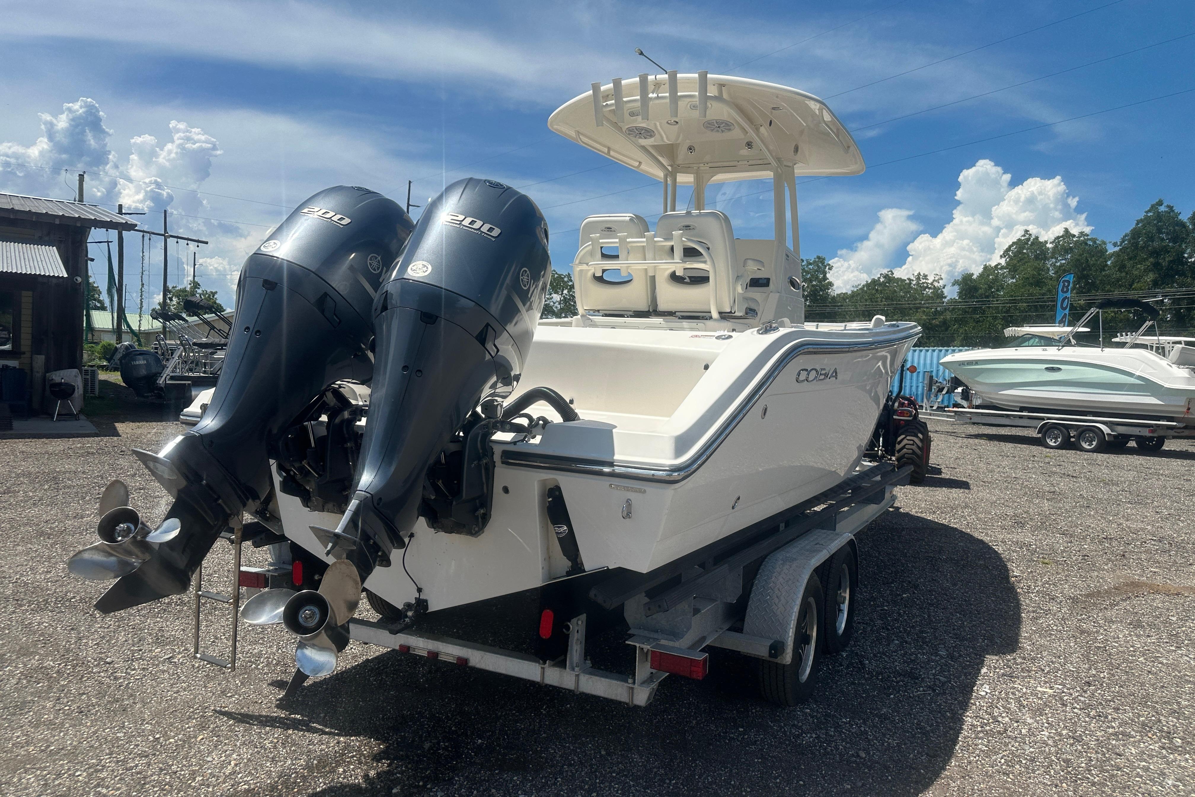 2023 Cobia 262 Center Console boat with dual engines on a trailer, outdoor setting.