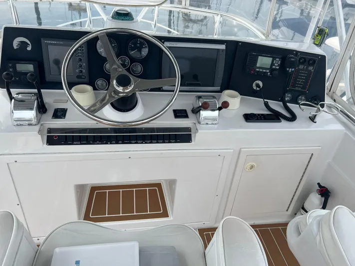 Dog Daze Yacht Photos Pics Helm of 2001 Jupiter 35 Convertible boat with steering wheel and navigation equipment.