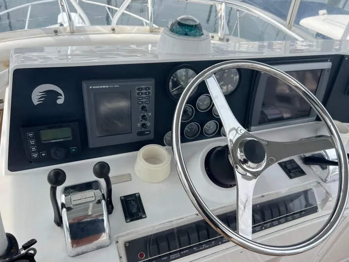 Dog Daze Yacht Photos Pics Control panel of a 2001 Jupiter 35 Convertible boat with steering wheel and navigation instruments.
