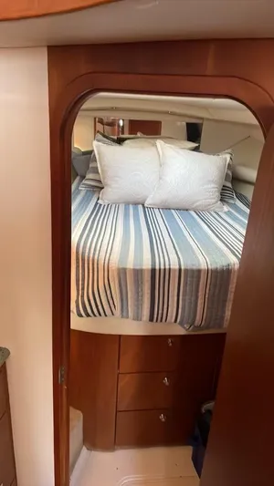 Dog Daze Yacht Photos Pics Cozy cabin interior of 2001 Jupiter 35 Convertible with striped bedding and wooden accents.