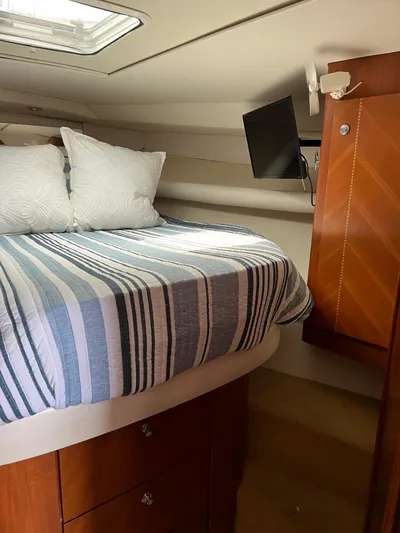 Dog Daze Yacht Photos Pics Cozy cabin interior of 2001 Jupiter 35 Convertible with striped bedding and TV.