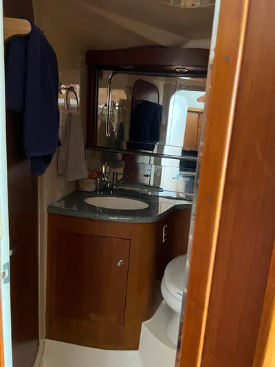 Dog Daze Yacht Photos Pics Bathroom interior of 2001 Jupiter 35 Convertible yacht with wooden cabinetry and modern fixtures.