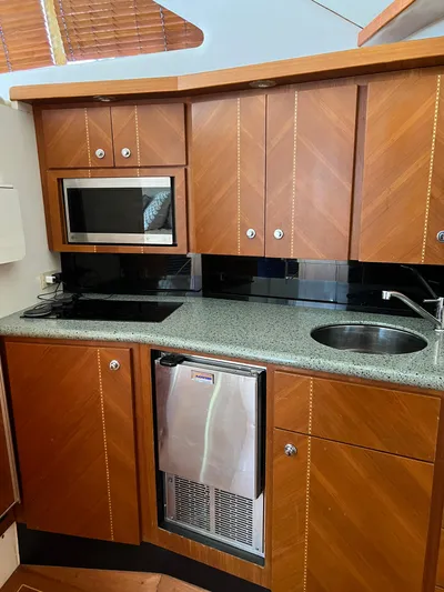 Dog Daze Yacht Photos Pics 2001 Jupiter 35 Convertible yacht kitchen with wood cabinets, microwave, sink, and mini fridge.