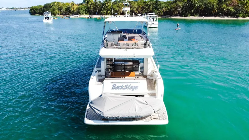  Yacht Photos Pics 2018 Prestige 560 Flybridge yacht on clear blue water near a tropical island.