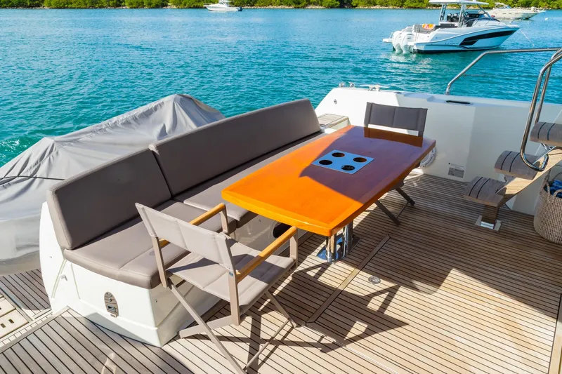  Yacht Photos Pics Prestige 560 Flybridge 2018 yacht deck with seating and table, overlooking serene blue waters.