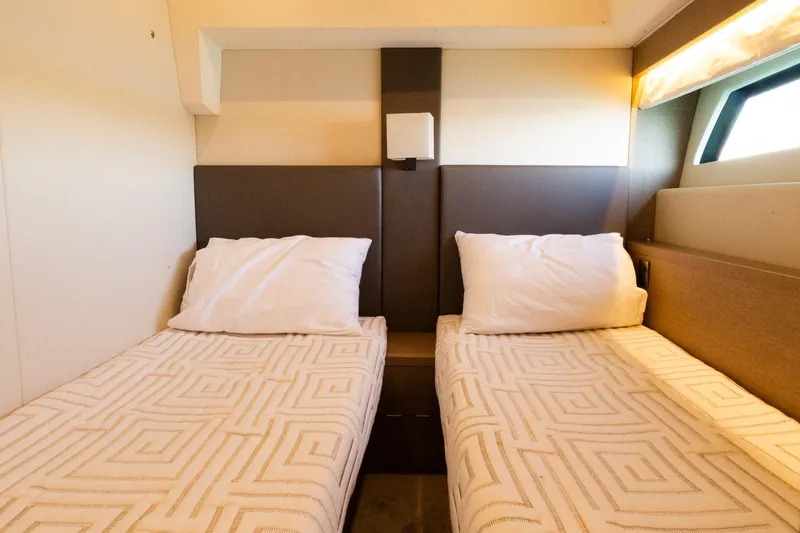  Yacht Photos Pics Twin beds in a 2018 Prestige 560 Flybridge yacht cabin, featuring modern design and cozy lighting.