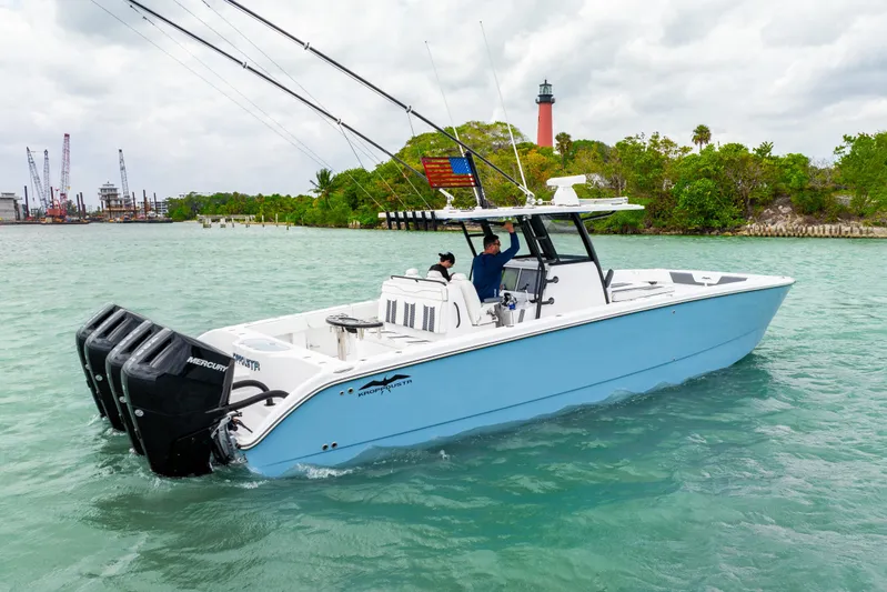 Kroppdustr Yacht Photos Pics 2023 Invincible 37 Catamaran on water, featuring triple Mercury engines, near lush shoreline.