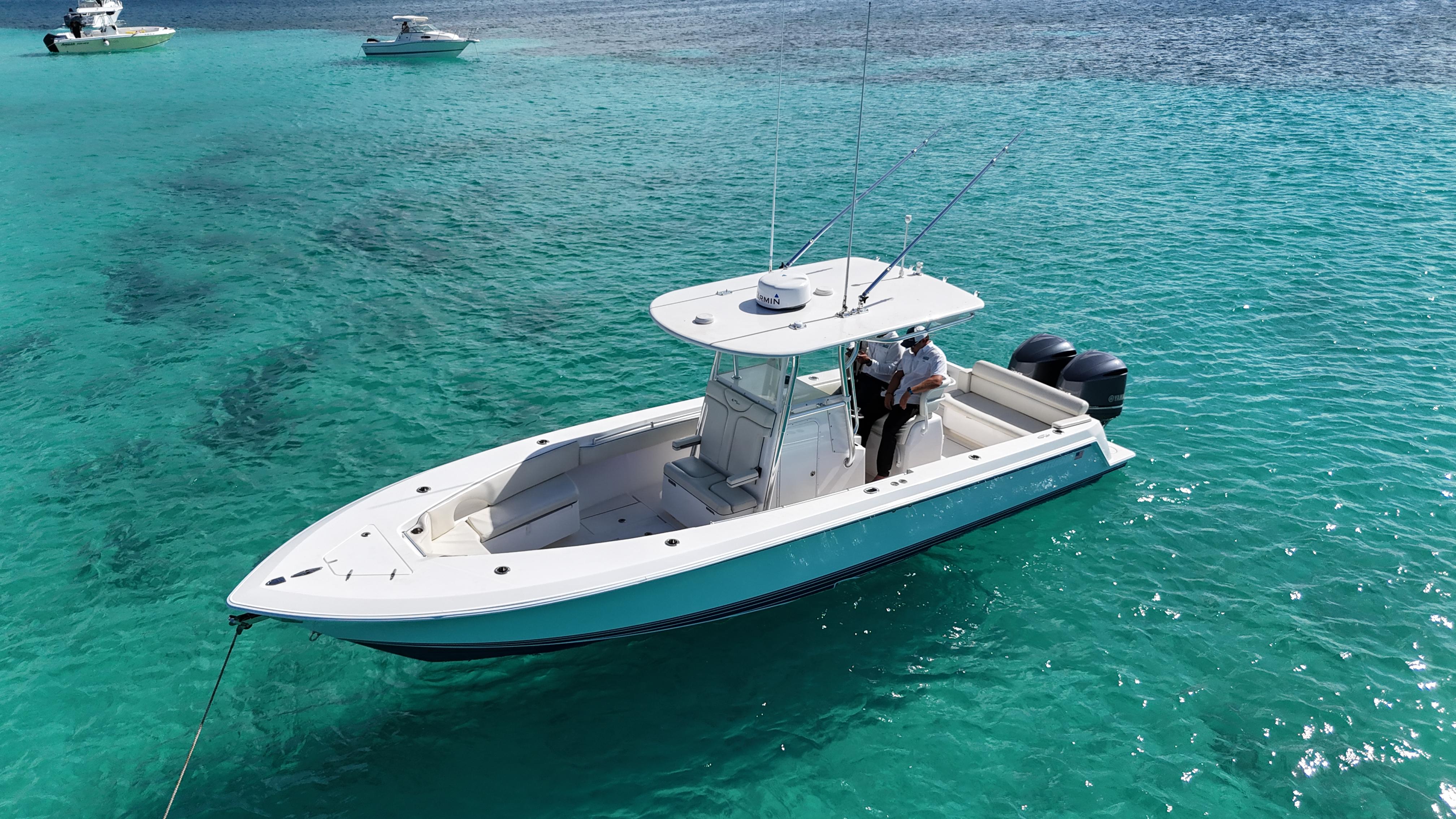 2013 Contender 30 ST boat on clear turquoise water, with two people onboard.