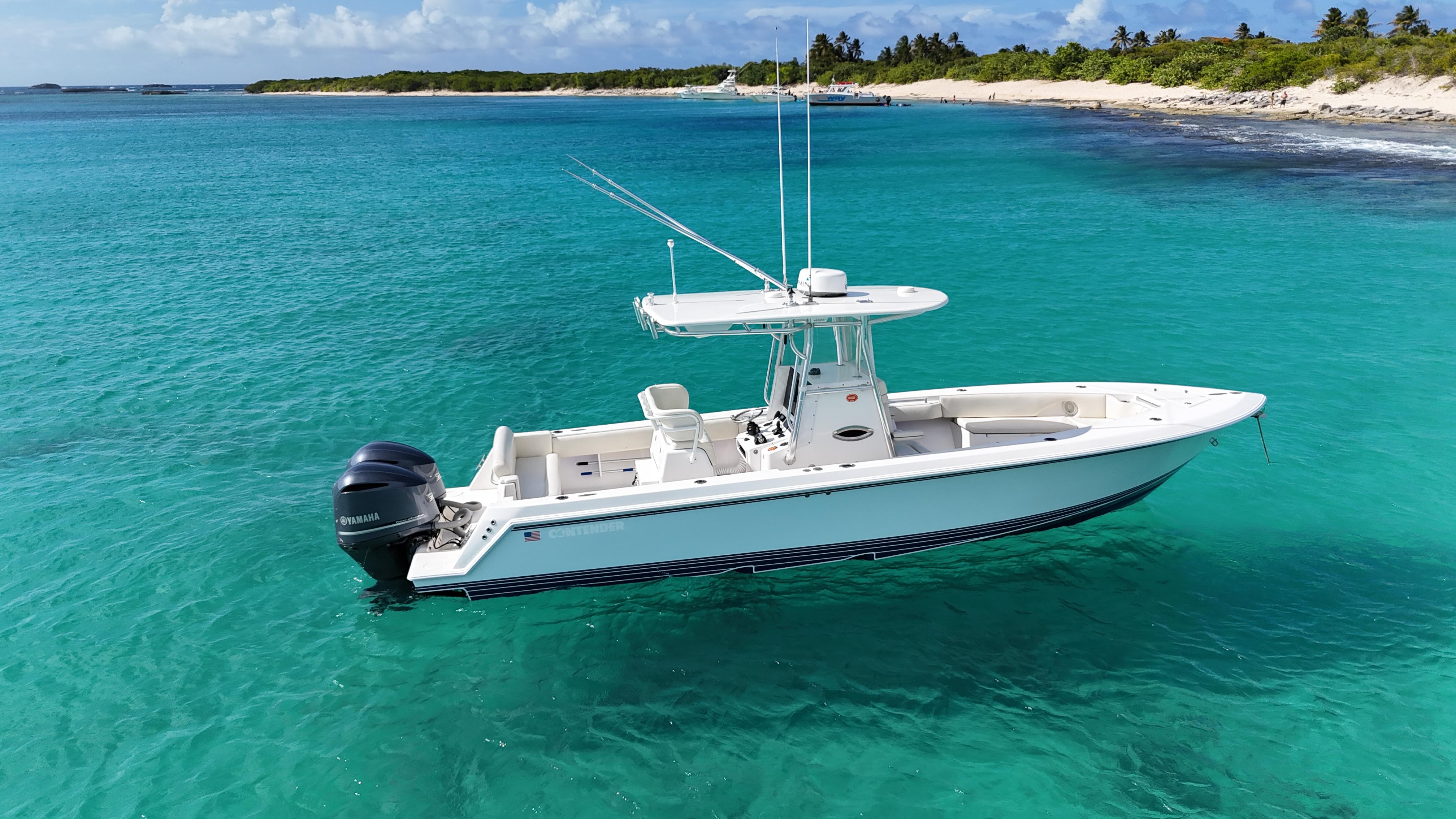 2013 Contender 30 ST boat on clear turquoise water near a sandy beach.