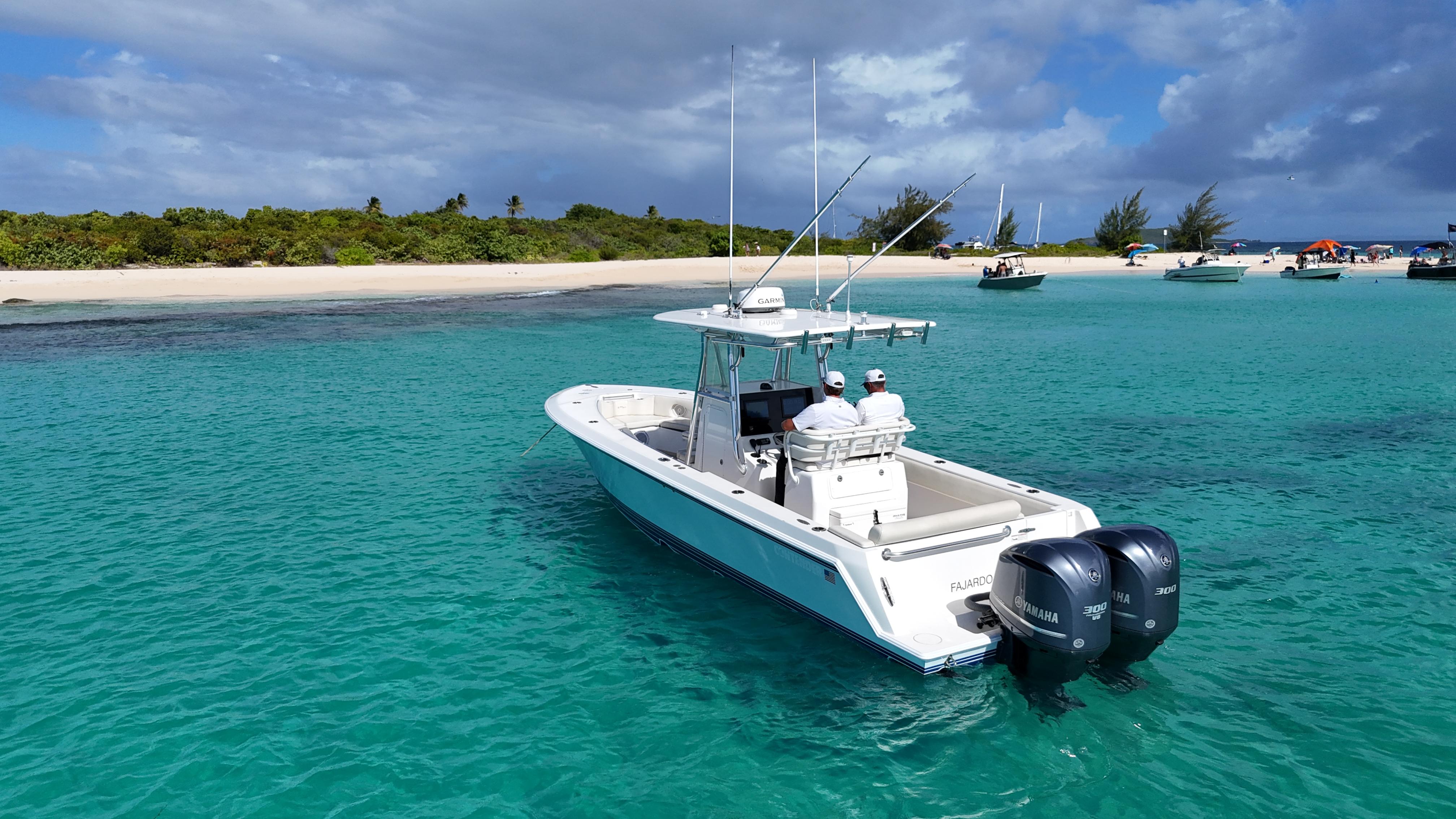 2013 Contender 30 ST boat cruising in clear turquoise waters near a sandy beach.