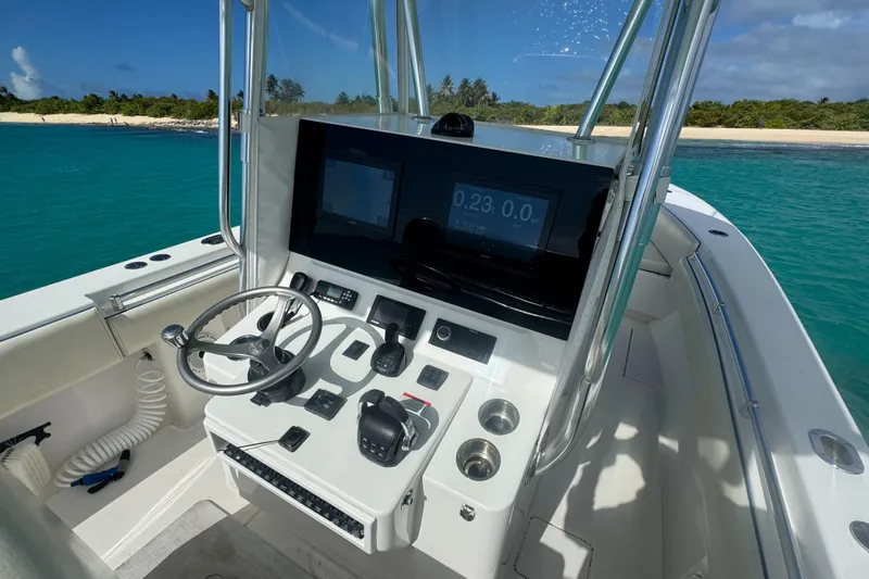  Yacht Photos Pics 2013 Contender 30 ST boat cockpit with steering wheel and control panel, near tropical shoreline.