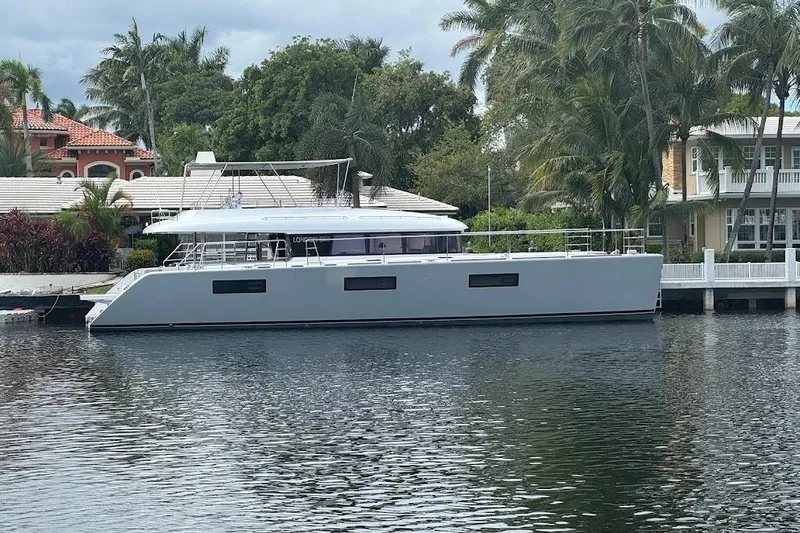 London Sky Yacht Photos Pics 2015 Lagoon Motor Yacht docked by waterfront homes, surrounded by lush greenery.