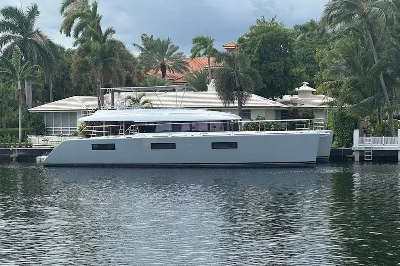 London Sky Yacht Photos Pics 2015 Lagoon Motor Yacht docked by a waterfront home with palm trees.