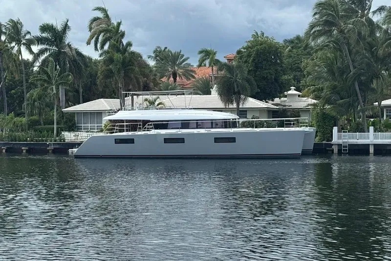 London Sky Yacht Photos Pics 2015 Lagoon Motor Yacht docked by a waterfront home with palm trees.