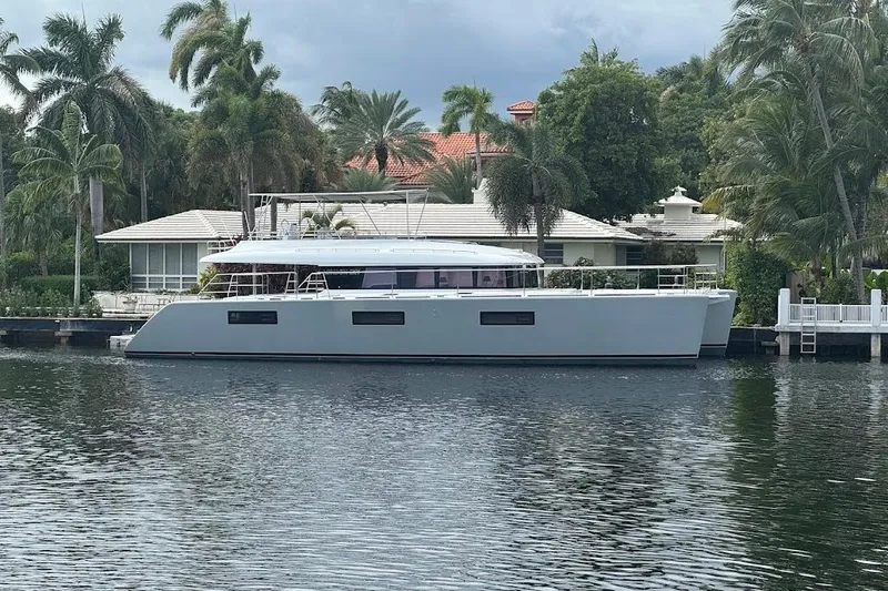 London Sky Yacht Photos Pics 2015 Lagoon Motor Yacht docked by a waterfront home with palm trees.