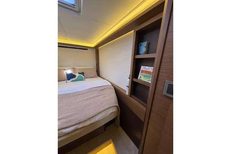  Yacht Photos Pics Cozy bedroom interior of 2020 Lagoon 46 yacht with ambient lighting and wooden shelves.