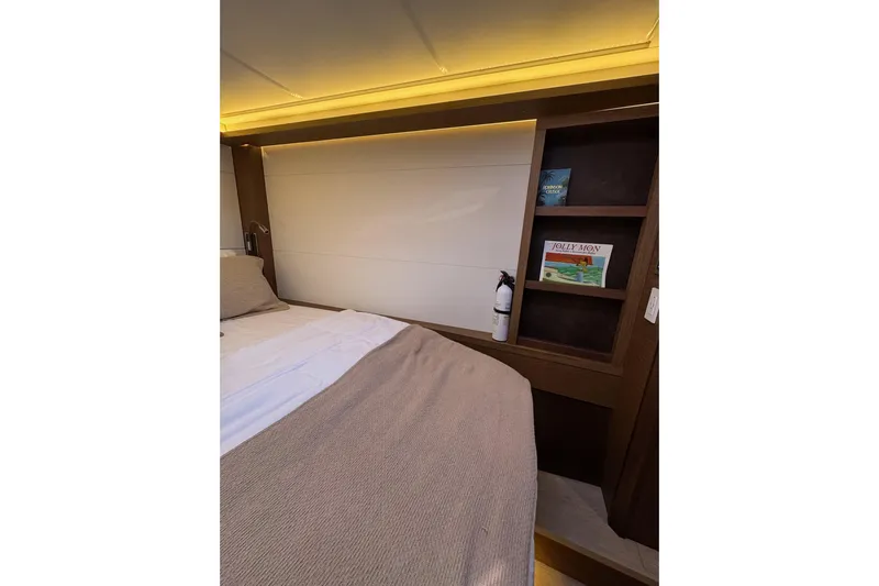  Yacht Photos Pics Cozy bedroom interior of 2020 Lagoon 46 yacht with books and fire extinguisher.