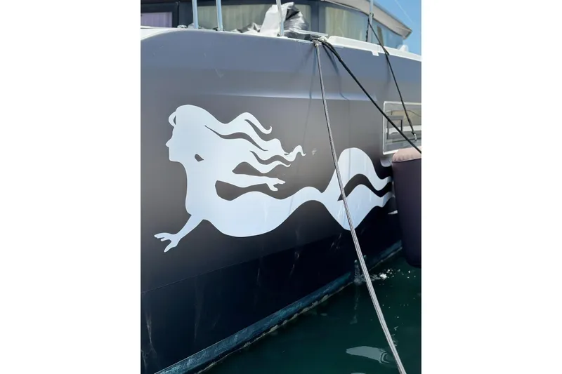  Yacht Photos Pics 2020 Lagoon 46 yacht with mermaid decal on hull, docked in marina.