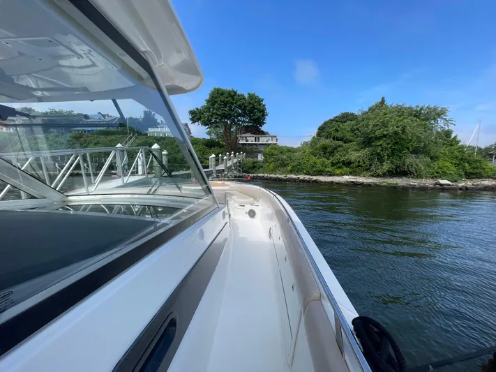  Yacht Photos Pics 2017 Boston Whaler 420 Outrage boat docked near lush greenery and calm waters.